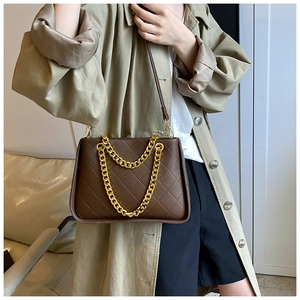 Détail du sac bandoulière matelassé marron foncé avec grosse chaîne dorée et sangle