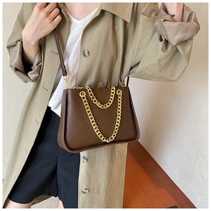 Détail d'un sac bandoulière marron foncé matelassé avec chaîne dorée et cuir