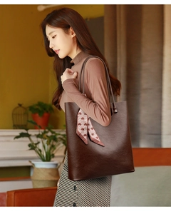 Brown leather tote bag with decorative heart pattern scarf shown on model shoulder