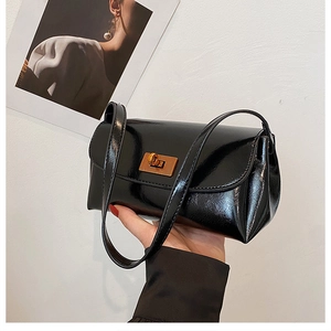 Detail of a vintage black patent leather shoulder bag with a gold rectangular metal lock