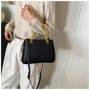 Détail du sac bandoulière matelassé noir avec poignée en chaîne dorée et cuir souple