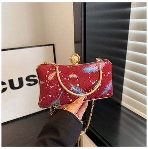 Détail du sac de soirée rouge pailleté avec fermoir perle et poignée chaîne dorée