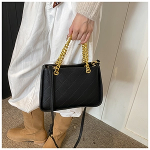Petit sac noir matelassé avec chaîne dorée porté sur une tenue décontractée chic