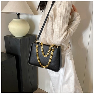 Détail du sac bandoulière en cuir noir matelassé avec chaîne dorée et surpiqûres