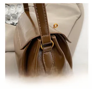 Close-up of golden metal strap rings on a brown oil wax leather shoulder bag