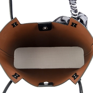 Interior view of tote bag showing magnetic closure, brown lining, and herringbone pattern base