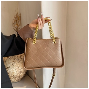 Détail d'un sac à main marron matelassé avec une chaîne dorée et une fine bandoulière