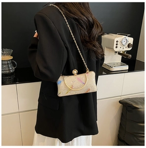 Détail du sac à main pailleté doré champagne avec motifs plumes et bandoulière chaîne