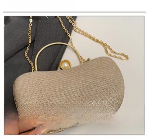 Détail macro d'une pochette de soirée pailletée champagne avec fermoir perle
