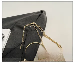 Détail d'un sac de soirée pailleté doré avec fermoir perle et bandoulière chaîne