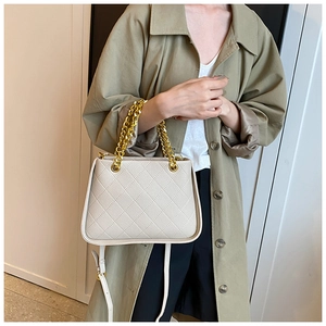 Détail du sac à main en cuir beige matelassé avec poignée chaîne dorée et sangle