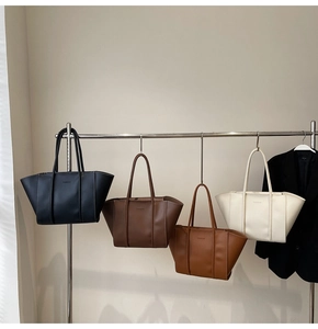Série de sacs cabas en cuir noir, marron et beige suspendus sur un portant de vêtements