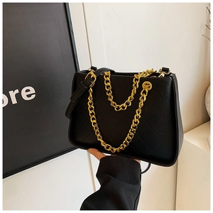 Détail du cuir grainé noir avec surpiqûres en losange et chaîne en métal doré