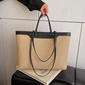Large beige woven tote bag with black leather trim and white stitching for women