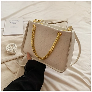 Détail d'un sac cabas blanc matelassé avec poignée chaîne dorée et texture grainée