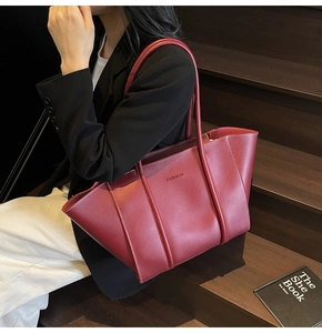 Détail d'un sac cabas bordeaux avec surpiqûres blanches et lettrage fashion