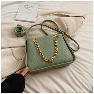 Détail d'un sac bandoulière matelassé vert clair en cuir texturé avec chaîne dorée décorative