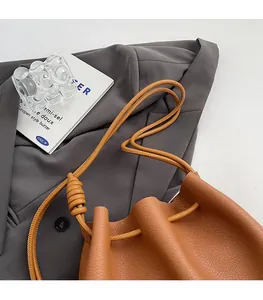 Detailed view of camel leather bucket bag with soft drawstring and knotted shoulder strap