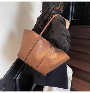 Détail d'un grand sac cabas en cuir marron avec inscription FASHION porté à l'épaule