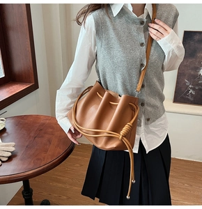 Detail of soft brown leather bucket bag with woven knot design and silver beads