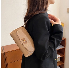 Detail of beige faux leather handbag with golden metal twist lock on black blazer