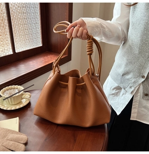 Detail of caramel bucket bag with drawstring closure and knotted shoulder strap detail
