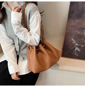 Detail of tan drawstring bucket bag showing premium leather texture and long shoulder strap