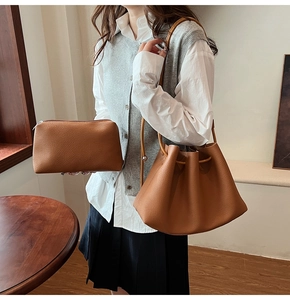 Detail of brown litchi pattern leather bucket bag and pouch set on a model