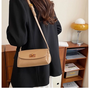 Close-up of vintage light brown glossy leather shoulder bag with gold metal buckle