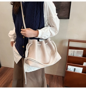 Close-up of beige leather bucket bag with a unique thick rope knot drawstring strap