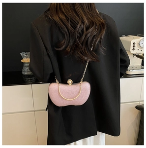 Détail du sac de soirée rose pailleté avec chaîne dorée et fermoir perle sur mannequin