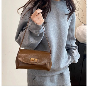 Detail of vintage brown leather handbag with gold metal clasp in home lifestyle setting