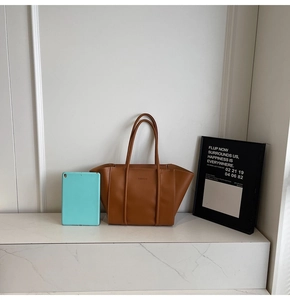 Détail d'un sac cabas en cuir marron montrant les ailes et le texte gaufré mode