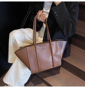 Détail du grand sac cabas vintage en cuir marron avec coutures blanches et logo mode