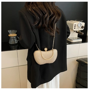 Détail du sac de soirée pailleté doré avec boucle en perles et poignée en métal