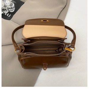 Close-up of the vintage brown shoulder bag showing its multi-compartment interior layout