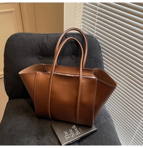 Gros plan sur un cabas en cuir marron avec logo FASHION sur un fauteuil en velours