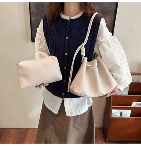 Detail of beige bucket bag and matching zipper pouch featuring litchi grain texture