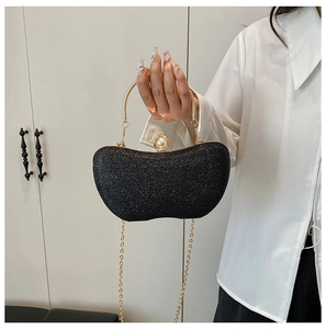 Détail d'une pochette à paillettes noires avec poignée dorée et fermoir en perle
