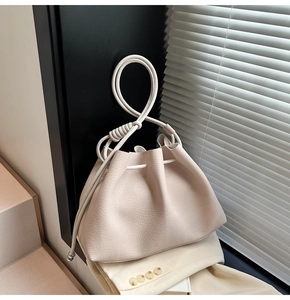 Detail of cream bucket bag with unique knotted rope handle and drawstring closure