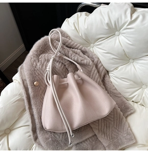 Detailed top view of beige leather drawstring bucket bag with elegant metal ball accents