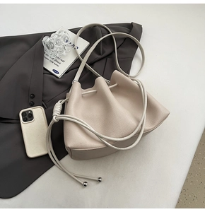 Detailed macro of cream bucket bag with drawstring closure and silver metallic beads