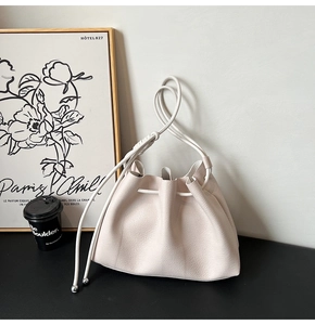 Detail of cream drawstring bucket bag with lychee texture leather and silver hardware