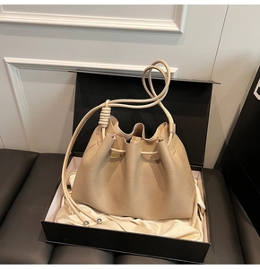 Detailed view of beige bucket bag with lychee grain leather and cord shoulder strap