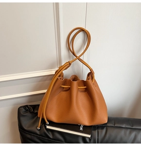 Detail of brown litchi pattern leather bucket bag featuring mustard yellow drawstring