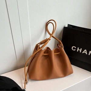 Chic caramel leather bucket bag with spiral handle and metallic ball detail
