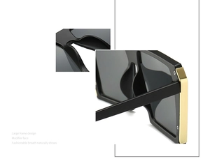Detail of matte black oversized sunglasses featuring golden metal trim on the side