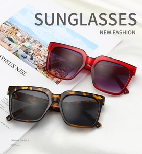 Detail of square oversized sunglasses in tortoiseshell and wine red on silk fabric