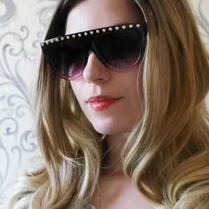Détail de lunettes de soleil oversize avec rivets dorés et verres dégradés violets