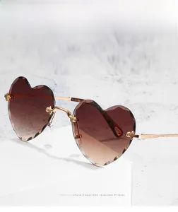 Close-up of heart-shaped rimless sunglasses with gradient lenses and gold metal temples